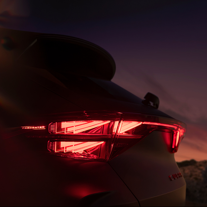 close up of the new cupra formentor's 2024 illuminated rear light showcasing angular design and a red glow against the sunset backround.​