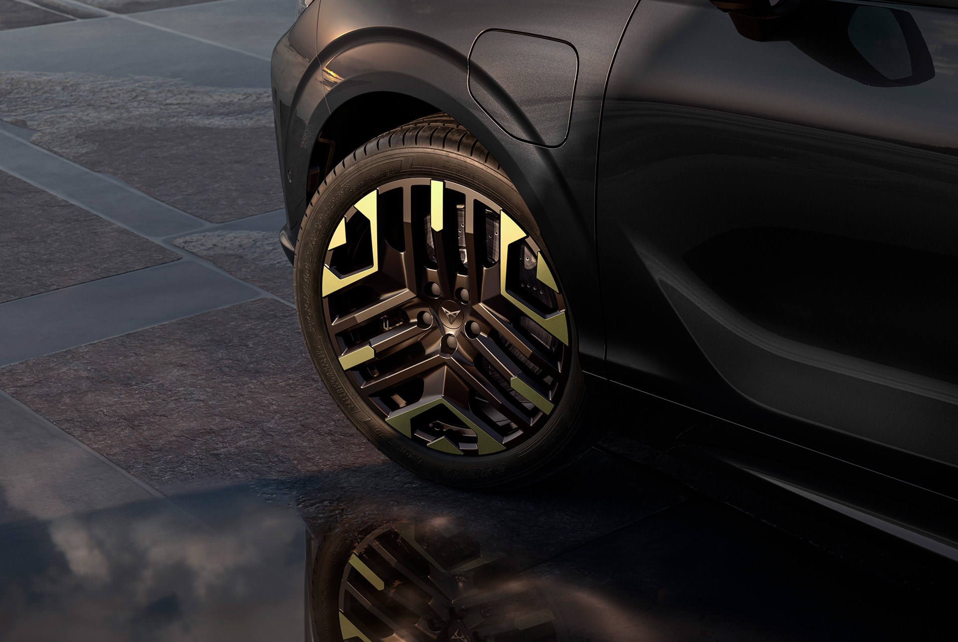 Left 20-inch sulfur alloy wheel on the cupra terramar from the new tribe edition, against a tiled, dark pavement to complement the glossy dark body