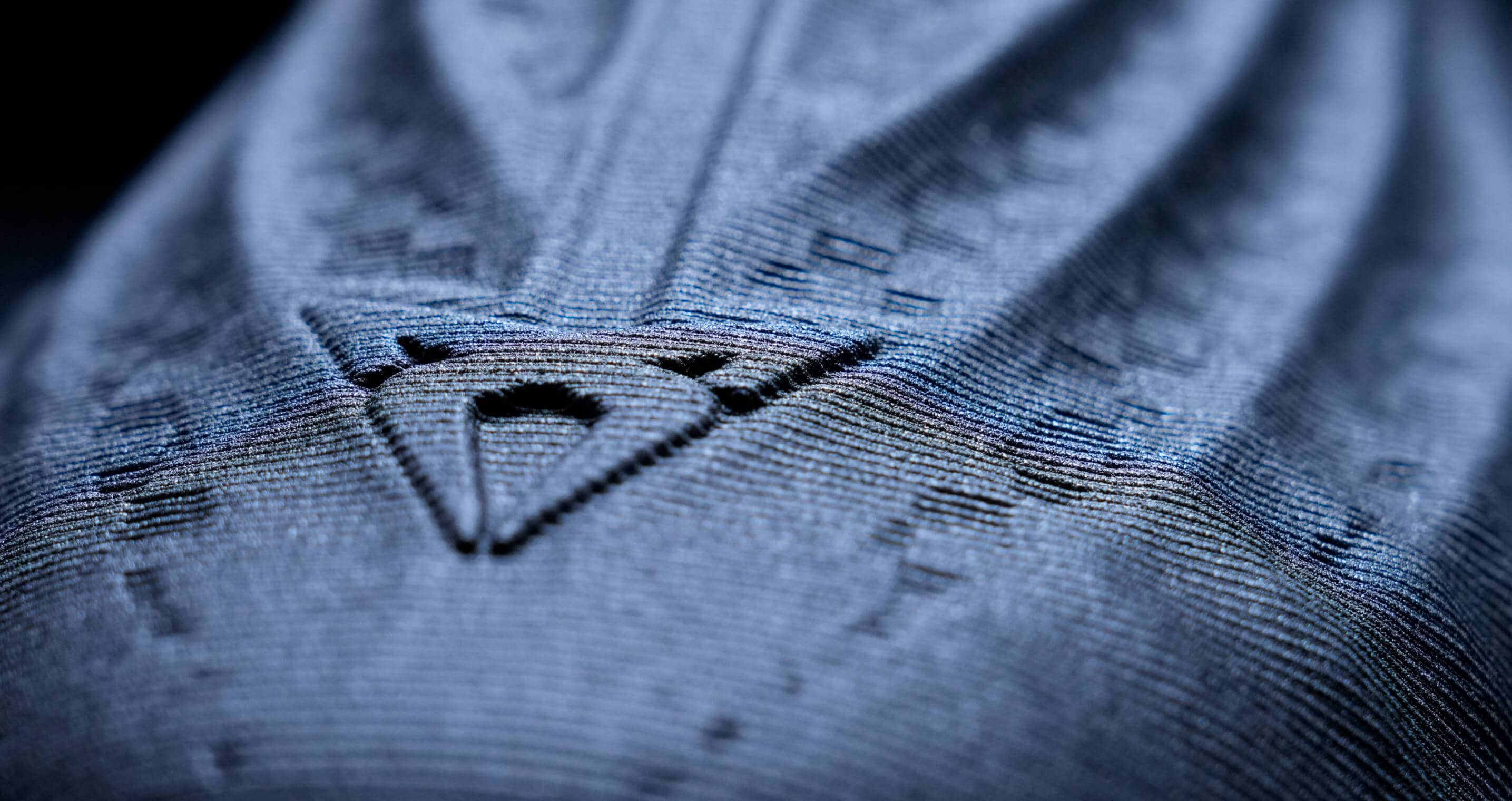 A close-up shot of a textured fabric with a prominent geometric pattern and logo.