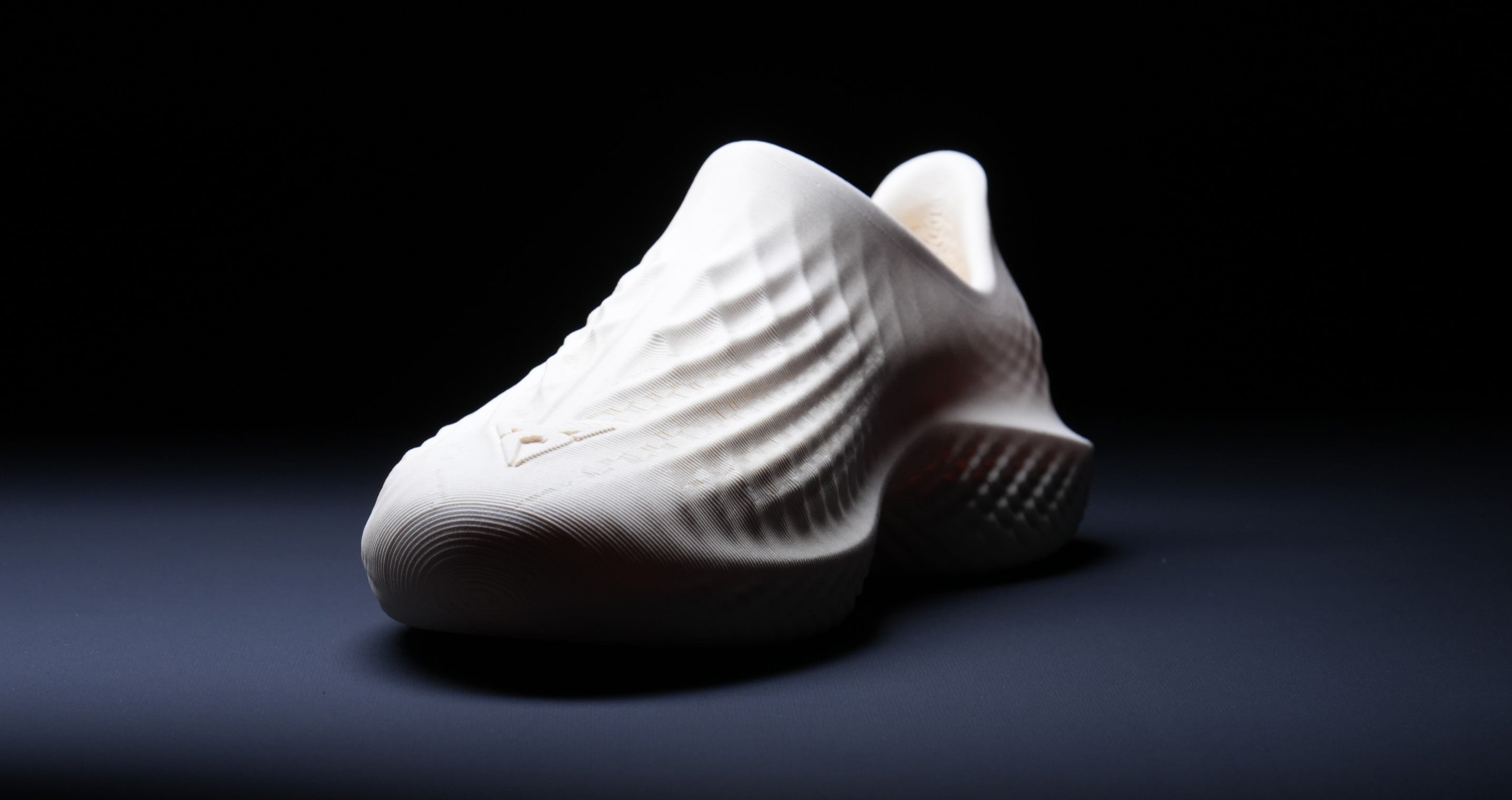 A white, textured shoe displayed in a product shot against a dark background.