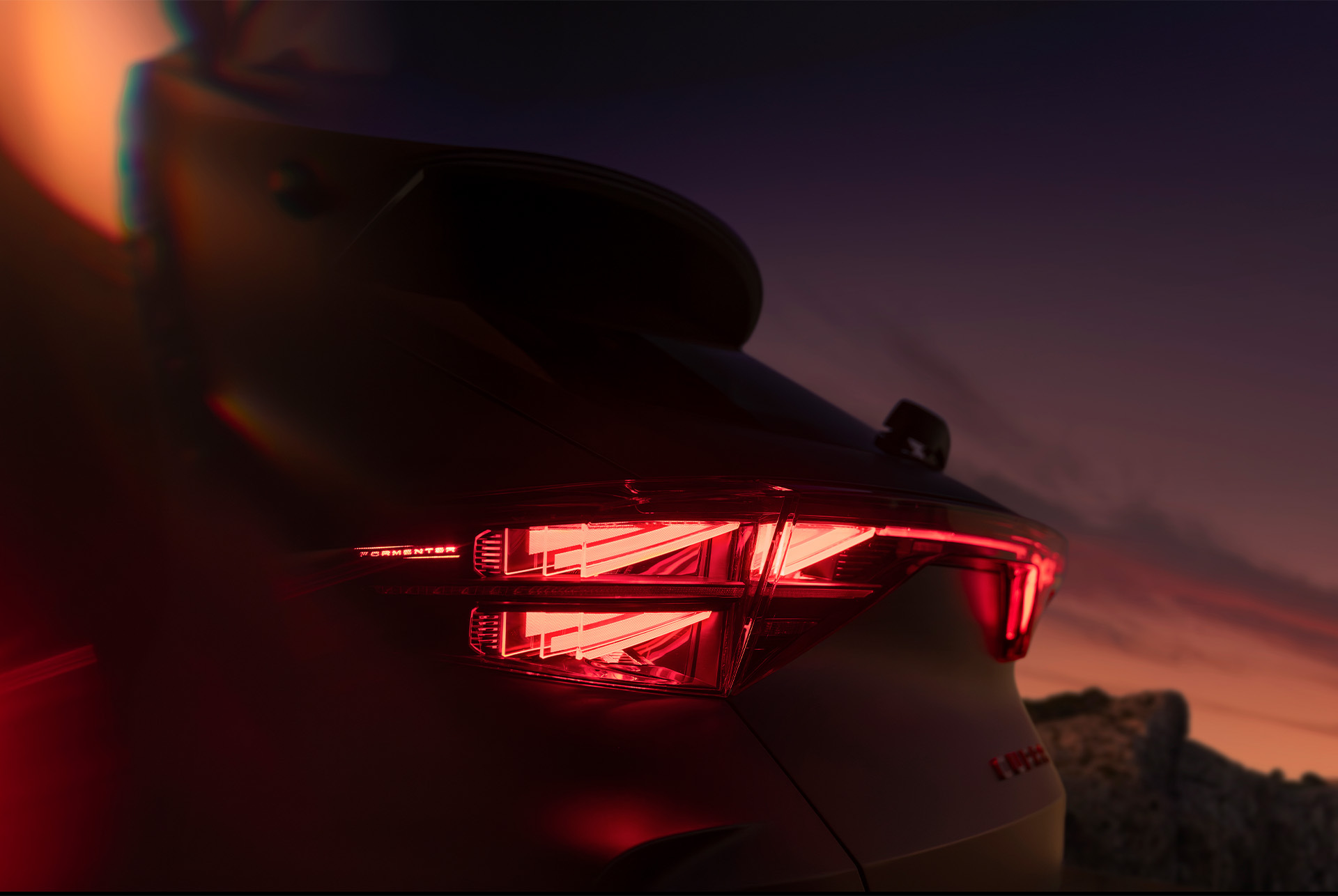 close up of the new cupra formentor's 2024 illuminated rear light showcasing angular design and a red glow against the sunset backround.