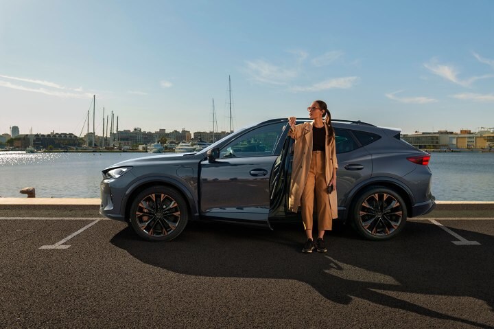 Woman exiting the cupra  tavascan obtained through classical credit leasing with no balloon payment.