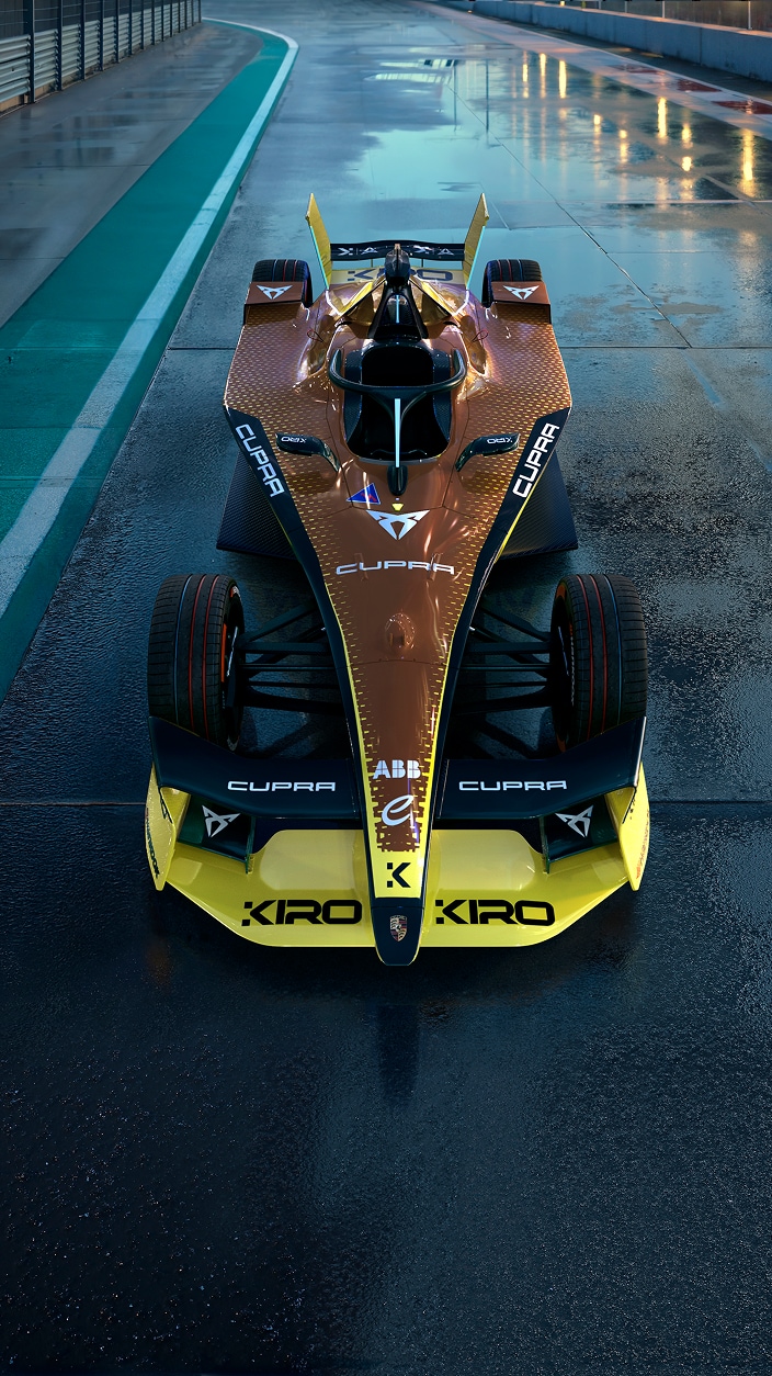 CUPRA electric race car with a copper and yellow design, parked on a wet racetrack.