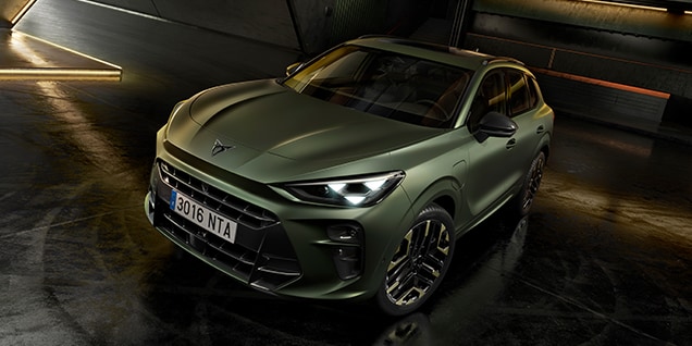 A green Cupra Terramar SUV is parked in a dark, industrial garage. The car is the main subject, with its front and passenger side visible.