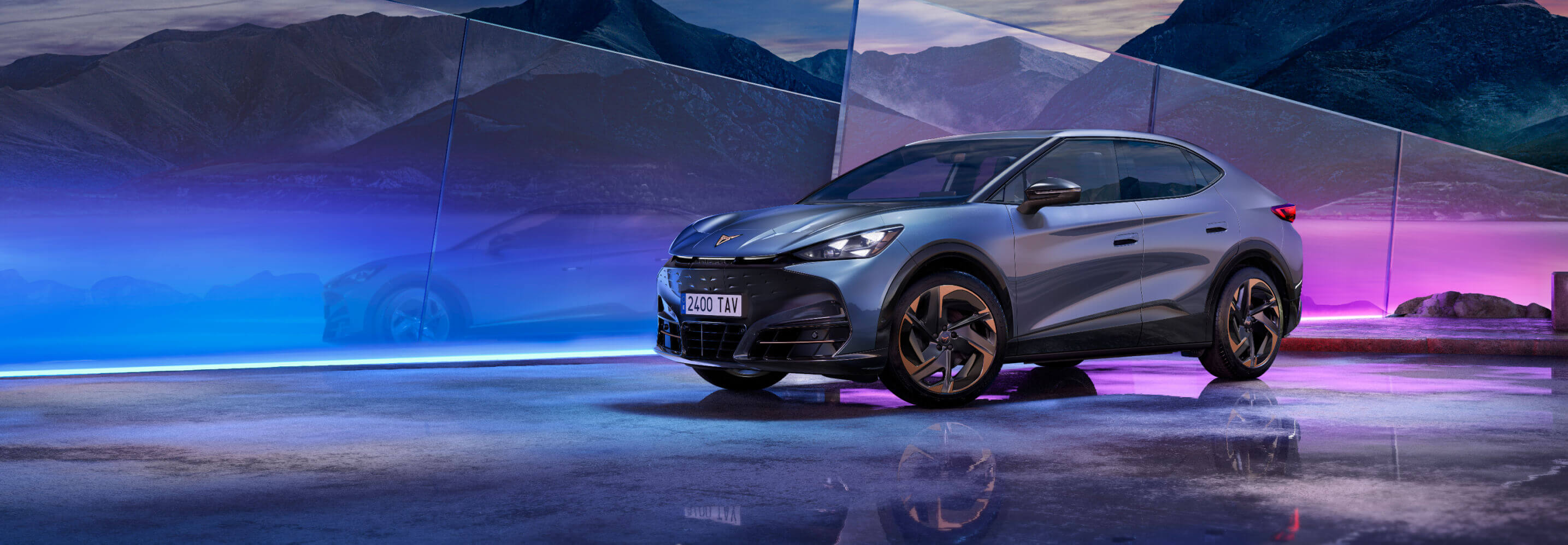 A grey CUPRA tavascan, on a front view angle, surrounded by multicolored dimmed lights.