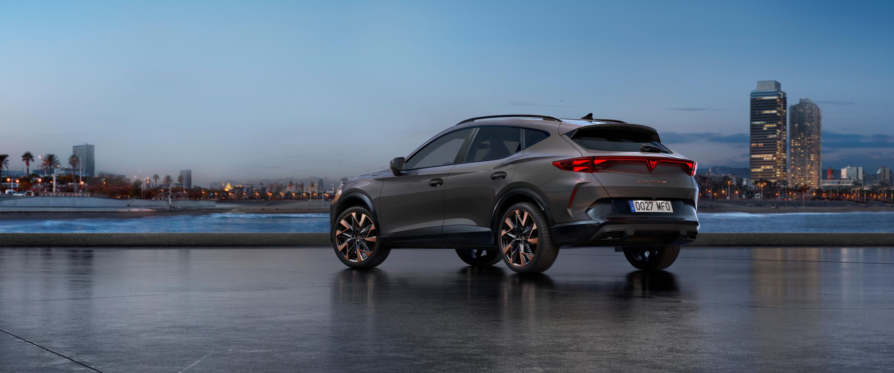What is a mild hybrid car — CUPRA Formentor PA in Graphene Grey, rear view parked by the water at sunset with city skyline.