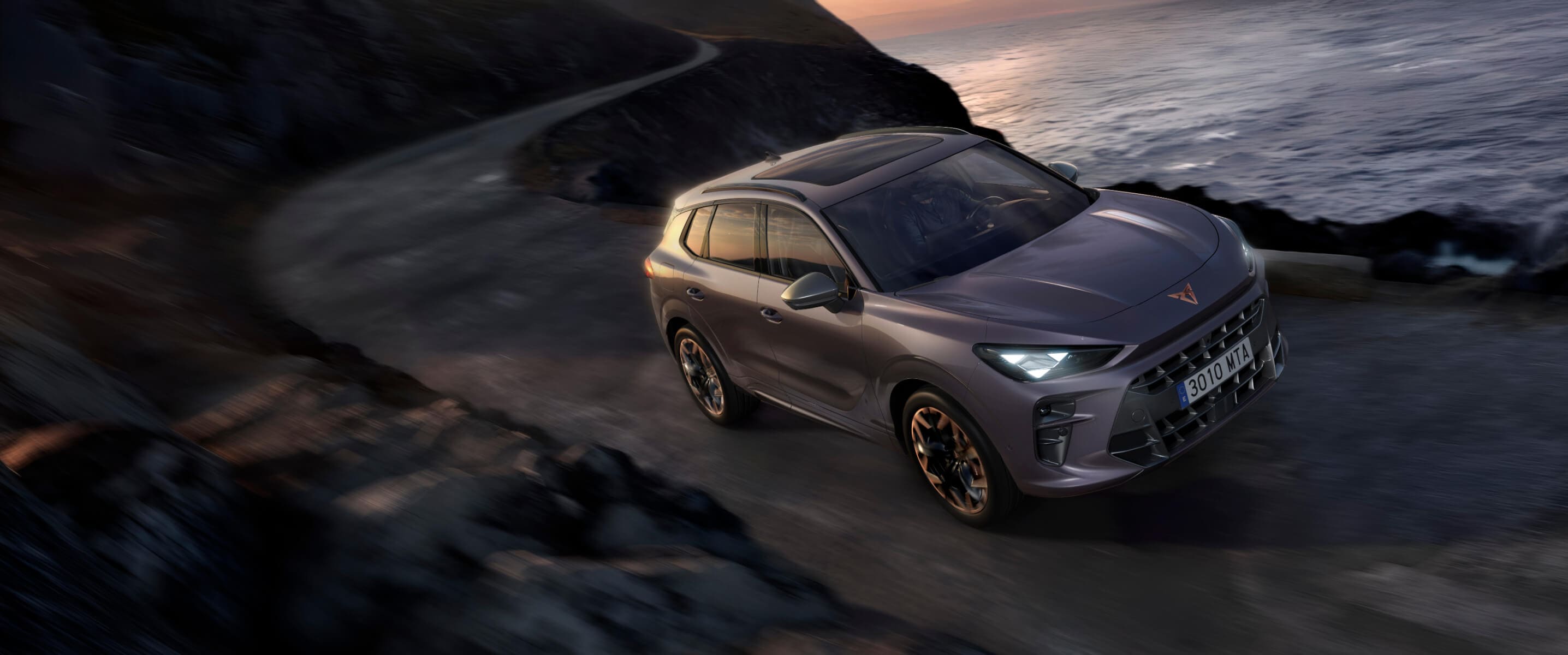 What is regenerative braking shown by CUPRA Terramar VZ plug-in hybrid driving on a coastal road at sunset, front angle view.
