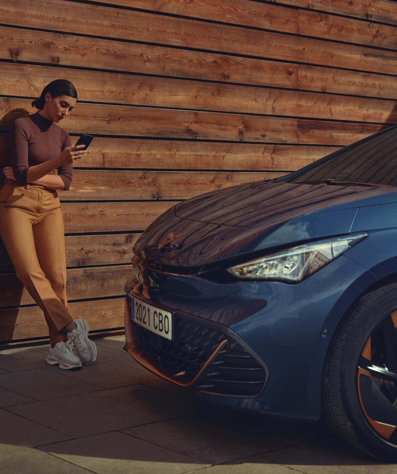 woman-standing-in-front-of-cupra-born-with-phone