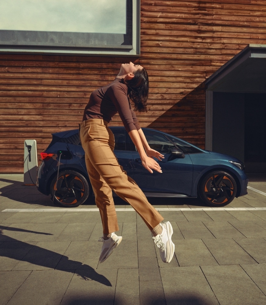 woman-jumping-cupra-Born-aurora-blue-colour-charging