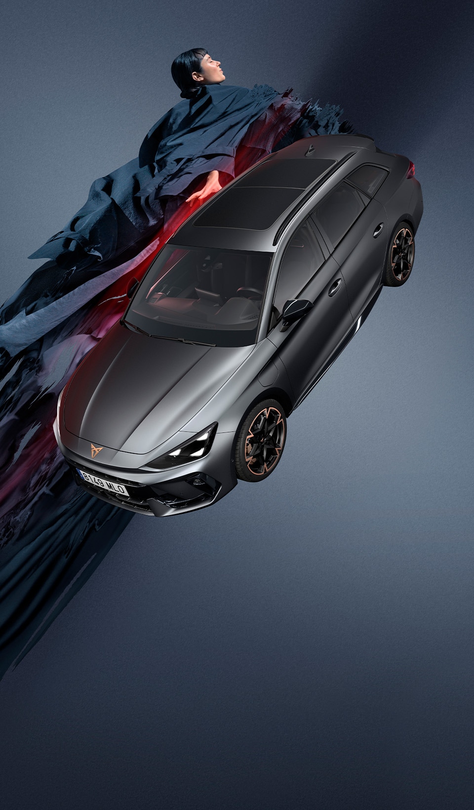 A CUPRA Leon Sportstourer shown from an elevated angle, with a person draped in dark, flowing fabric that creates a dynamic, red-lit trail beside the car.