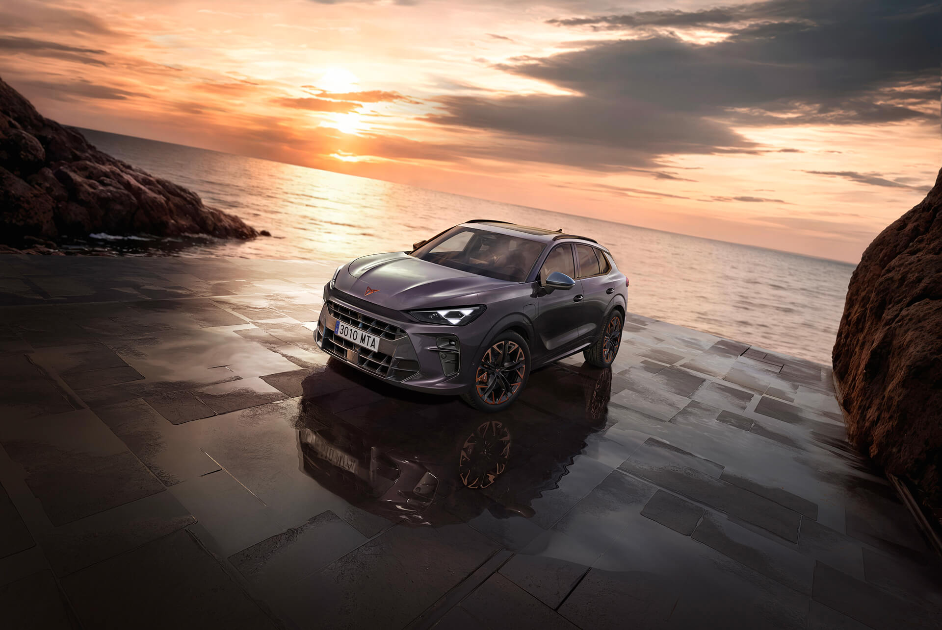 A dark gray Cupra Terramar SUV, front view, is parked on a reflective surface near a rocky shoreline at dusk or dawn. 